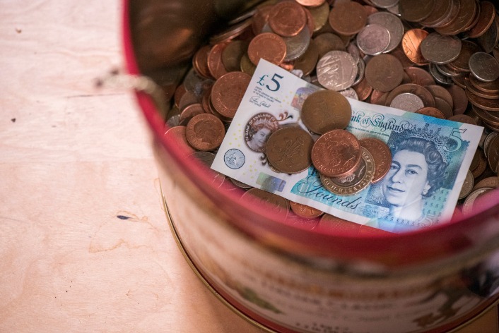 A basket holding a pile of coins and a £5 note